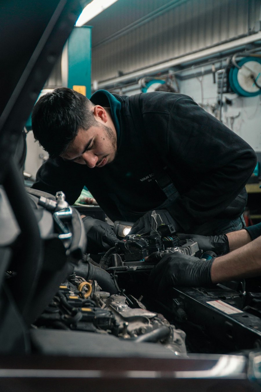 A mechanic working under the open bonnet of a car