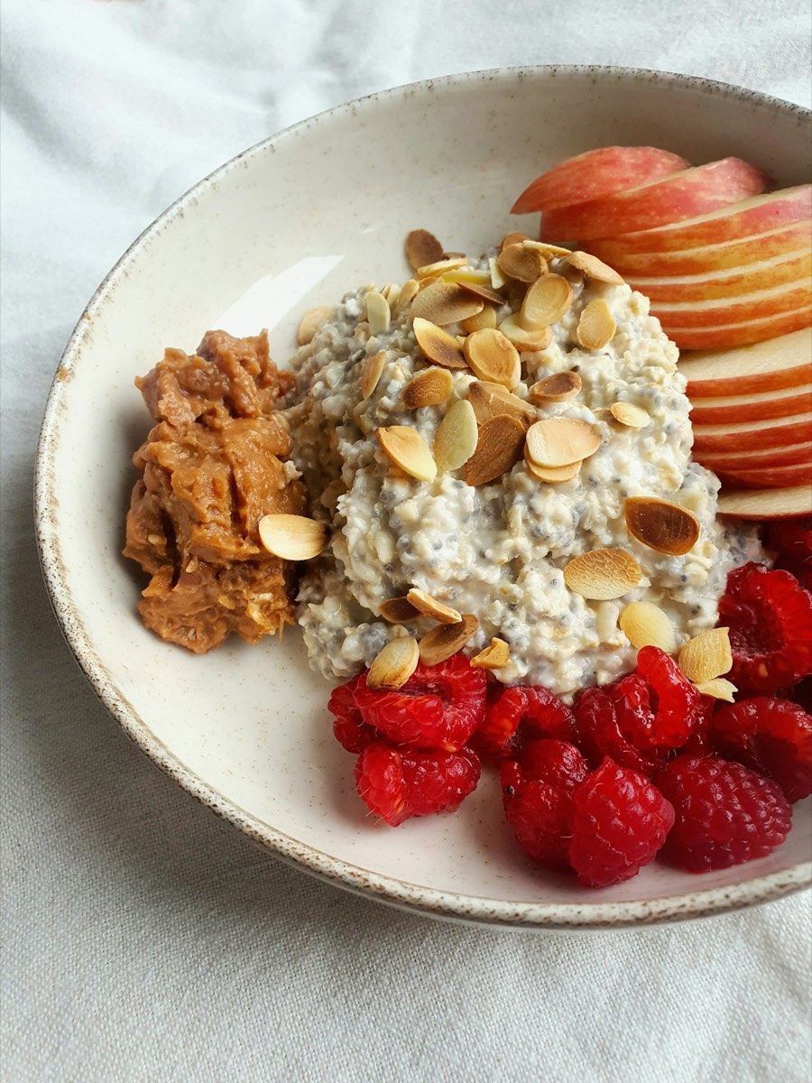 A bowl of overnight oats with apple, raspberries and almonds